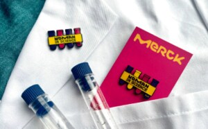 Pin with glittering yellow and purple test tube on a white background