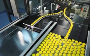 Conveyor belts in a factory with a stream of yellow bottle caps moving along them, highlighting the efficiency and automation in manufacturing