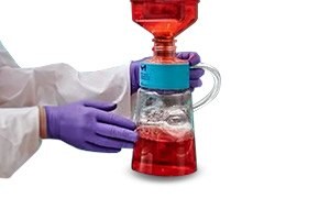 A scientist wearing purple gloves holds a red filter.