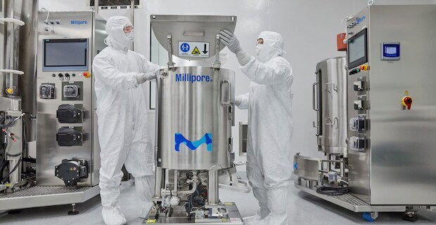 Researchers work in a GMP setting wearing full safety suits, masks and eye protection