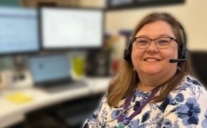 Paula Shivley sits at her desk with three screens behind her.