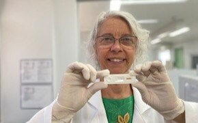 Dr. Samira Bührer wears glasses, gloves and holds up a rapid test for Hansen’s disease.  