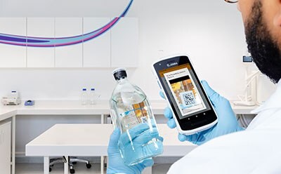 Lab worker looking at a phone and a bottle