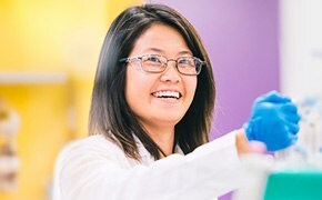 Woman laboratory technician with PPE holding an Erlenmeyer